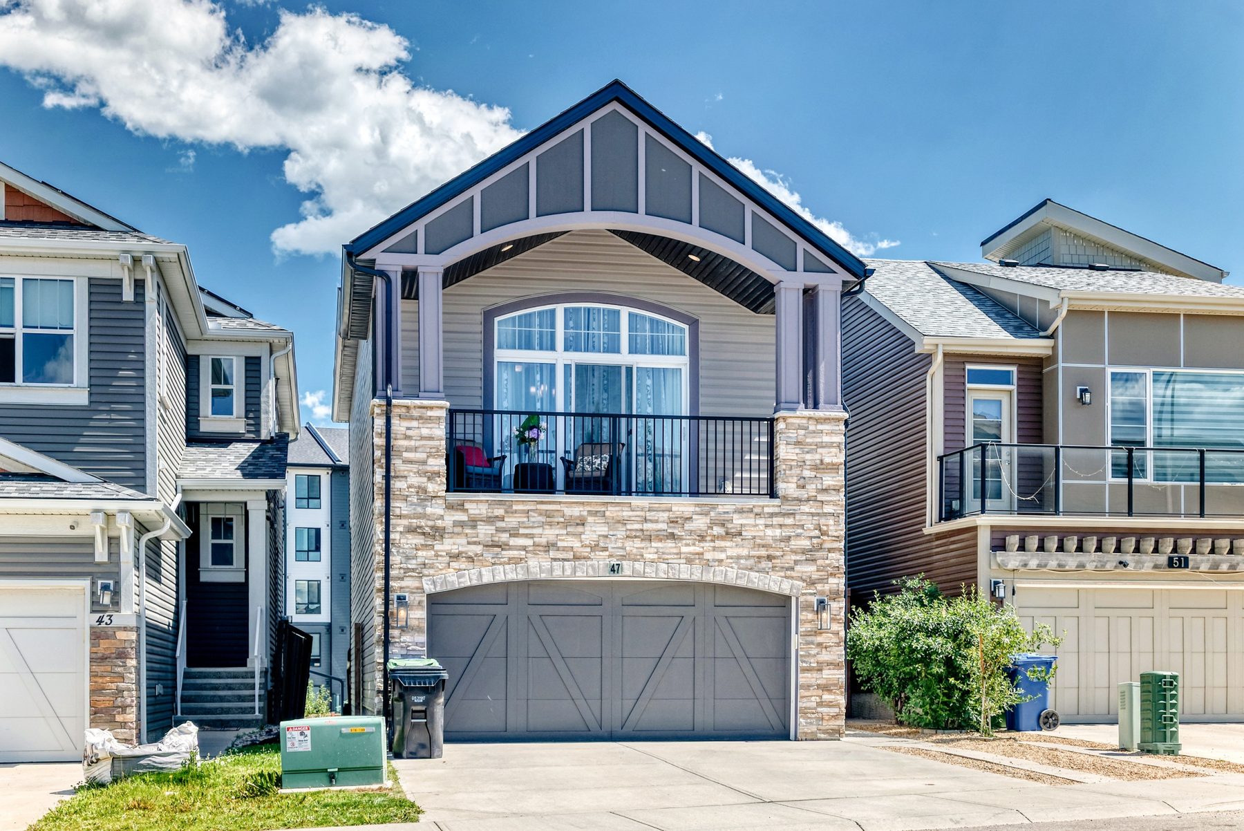 Exterior of 47 Sage Bluff Mews NW, a two-storey home with stone accents and double garage in Sage Hill, Calgary